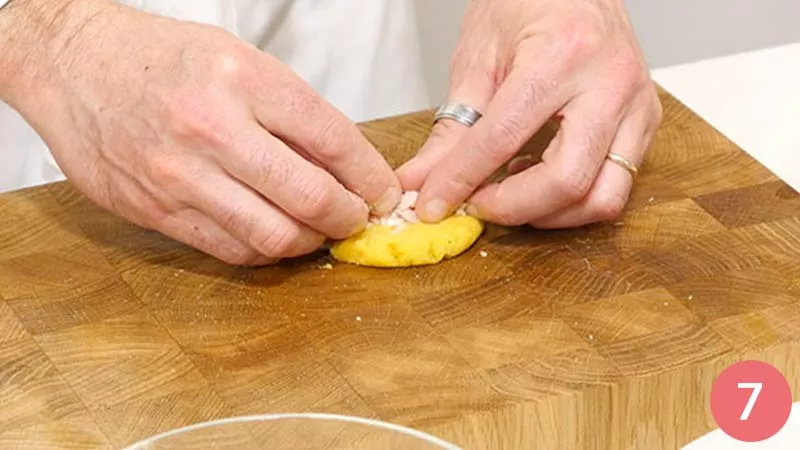 Preleviamo ora un'abbondante cucchiaiata di composto di patate, schiacciamo delicatamente con le mani e poniamo al centro un po' di prosciutto cotto.
